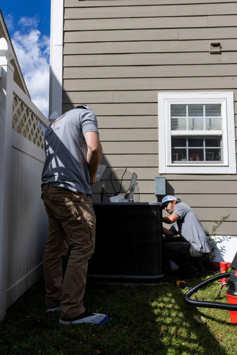 Technician checking refrigerant lines on a condenser