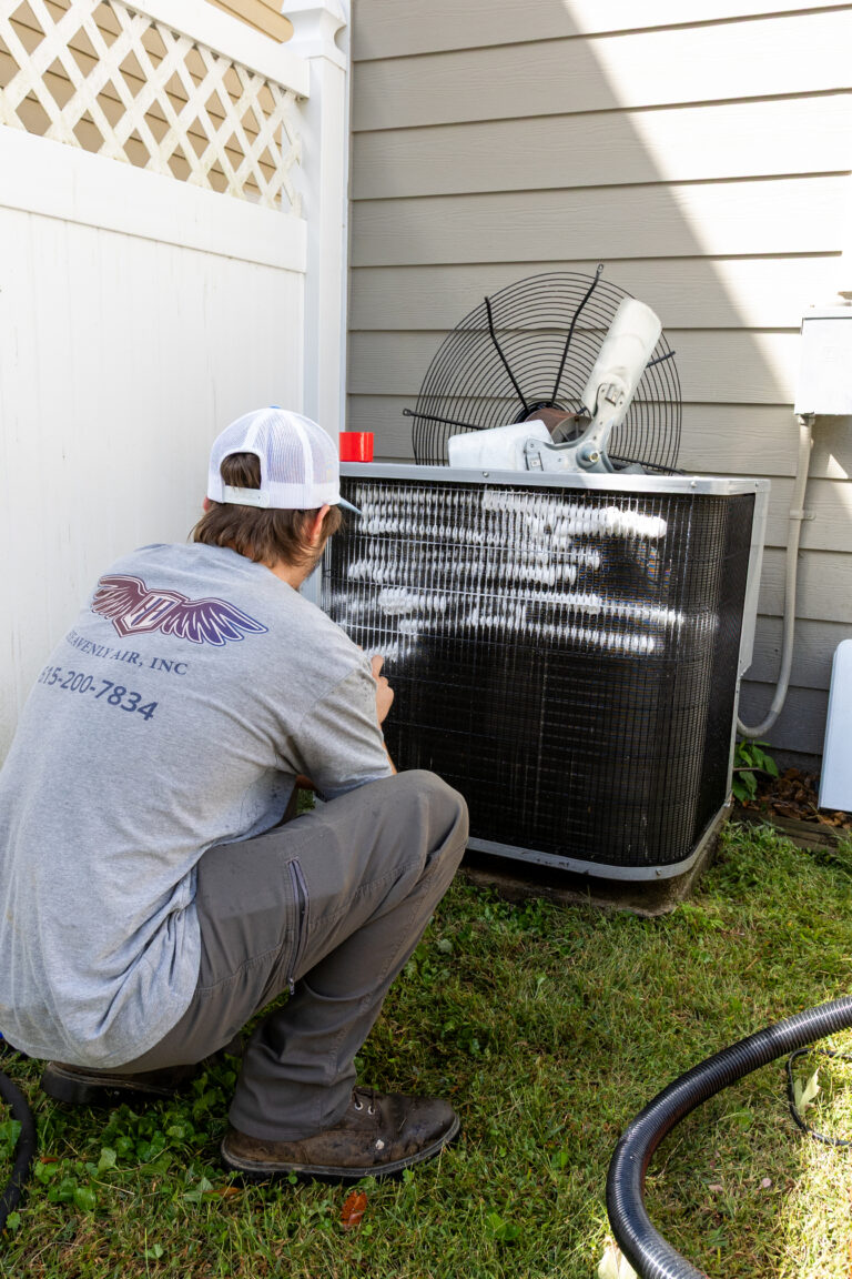 Technician cleaning an outdoor AC coil